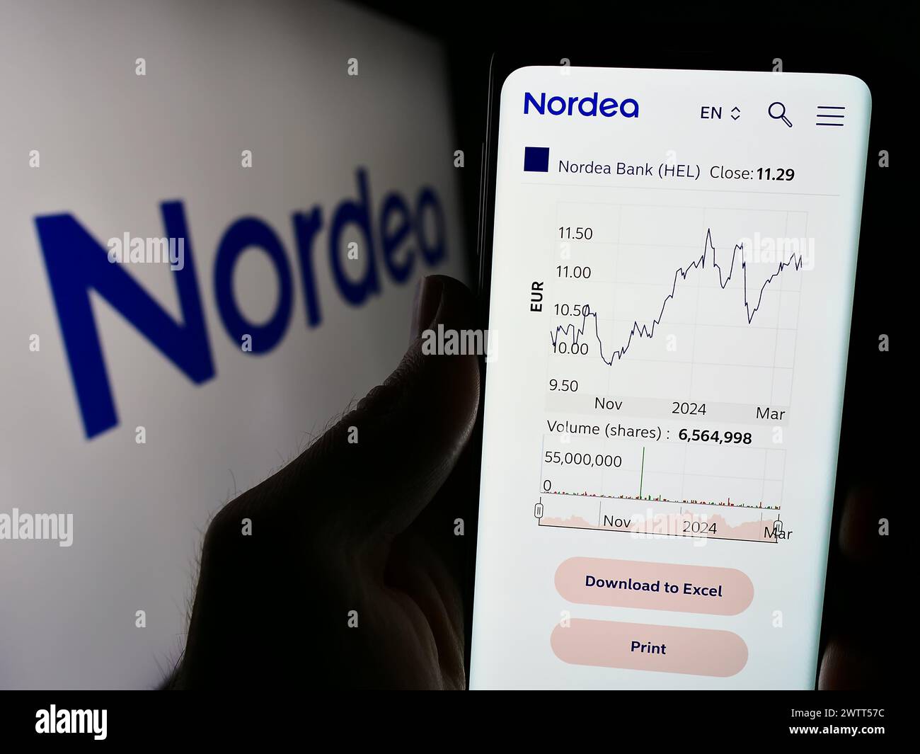 Person holding cellphone with webpage of Finnish financial services company Nordea Bank Abp in front of logo. Focus on center of phone display. Stock Photo