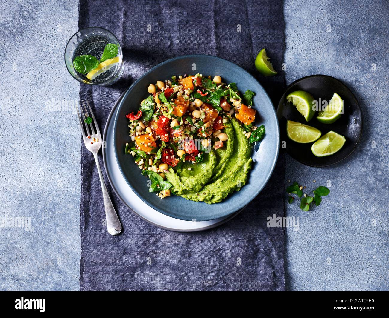 A vibrant green avocado puree topped with a colorful quinoa salad on a stylish plate. Stock Photo