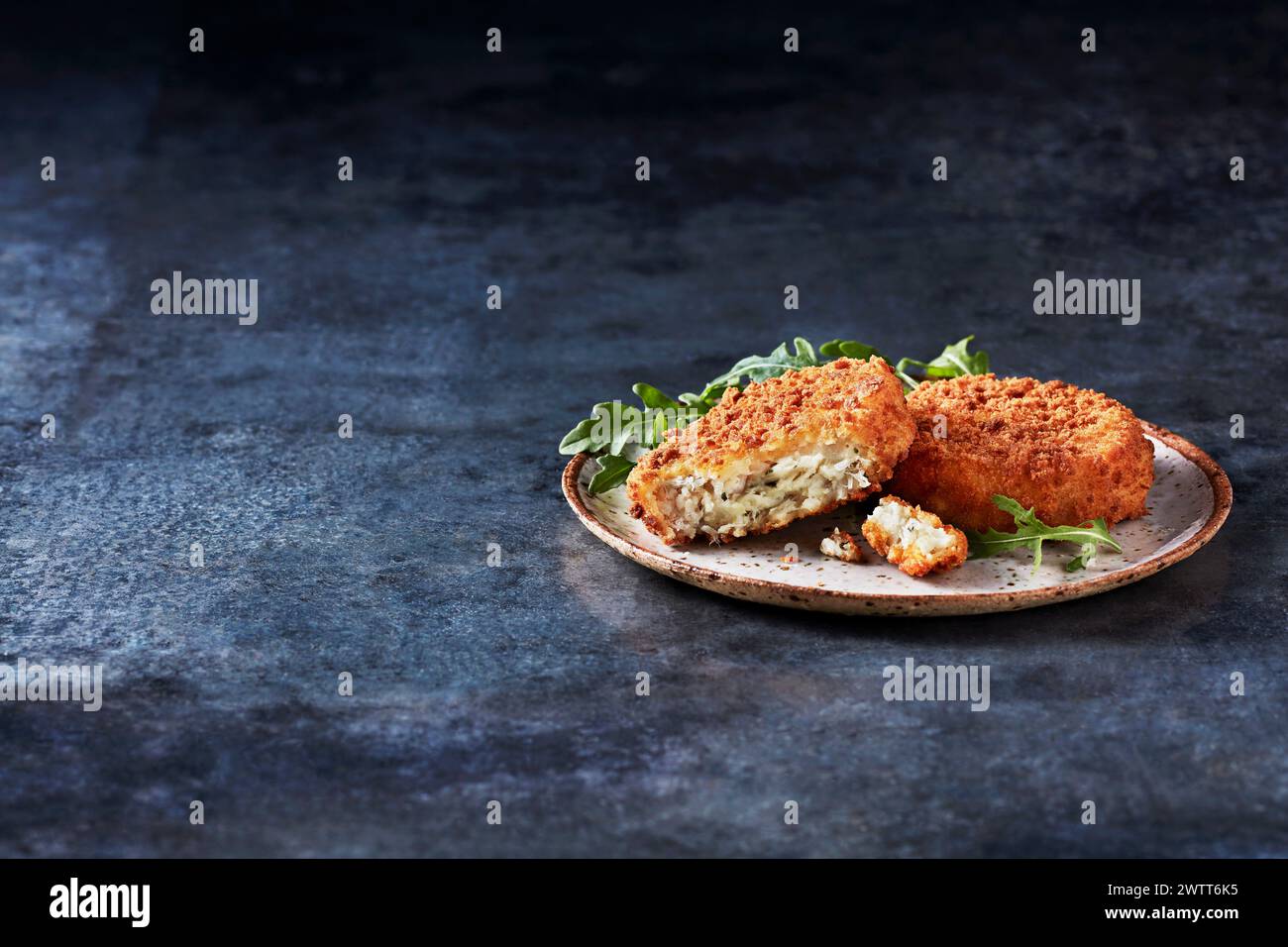 A delectable serving of crispy croquettes on a rustic plate garnished with fresh greens Stock Photo