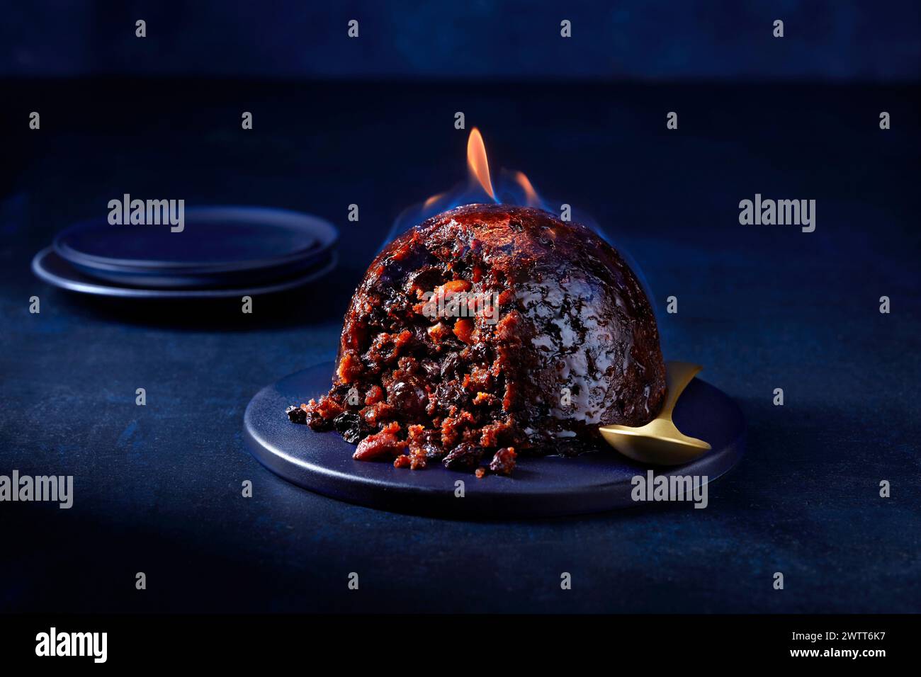 Flaming Christmas pudding on a festive table setting. Stock Photo