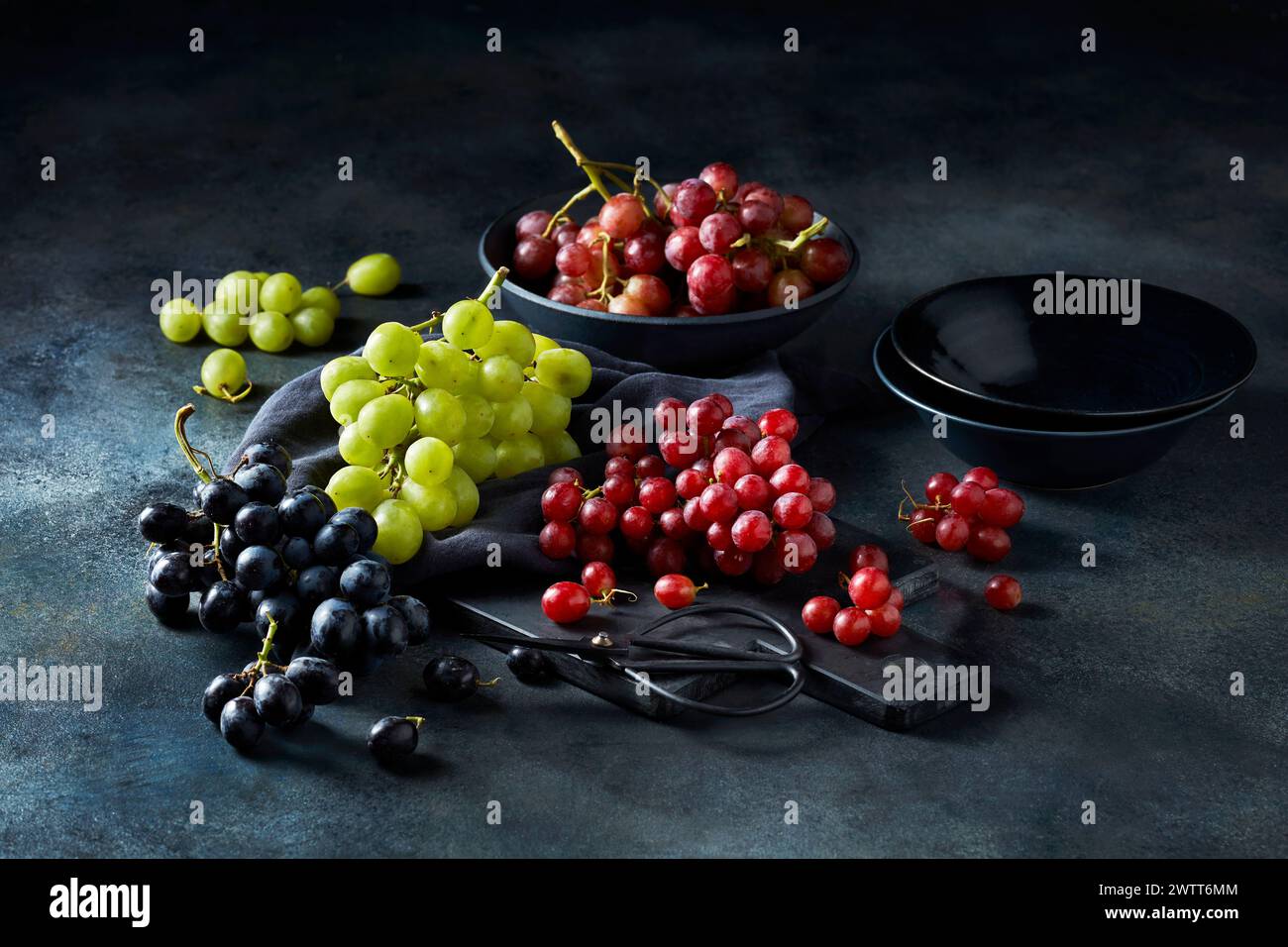 Assorted fresh grapes on rustic kitchen table Stock Photo