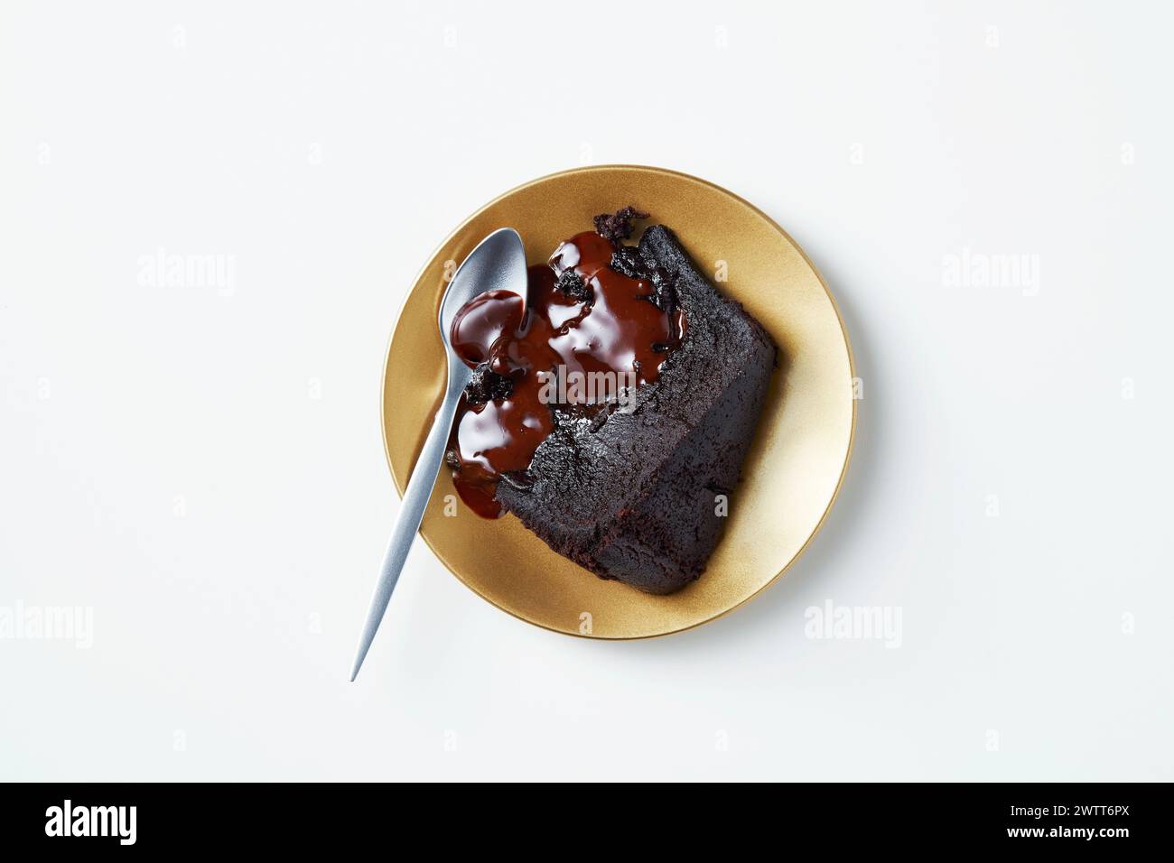 A slice of delectable chocolate cake oozing with rich sauce on a golden plate. Stock Photo