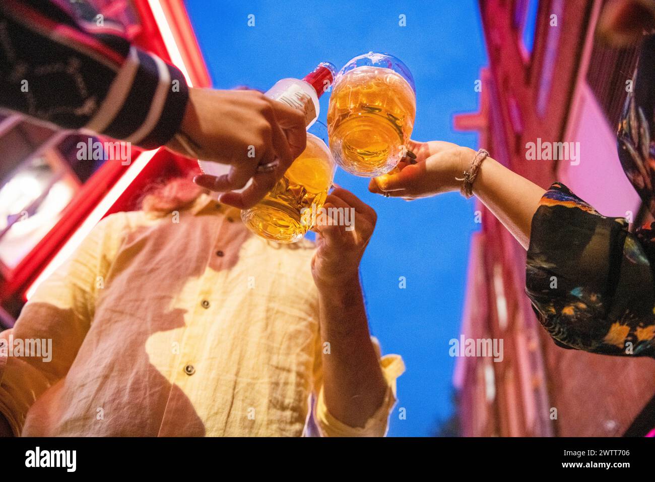 Friends toasting with beer on a vibrant city night. Stock Photo