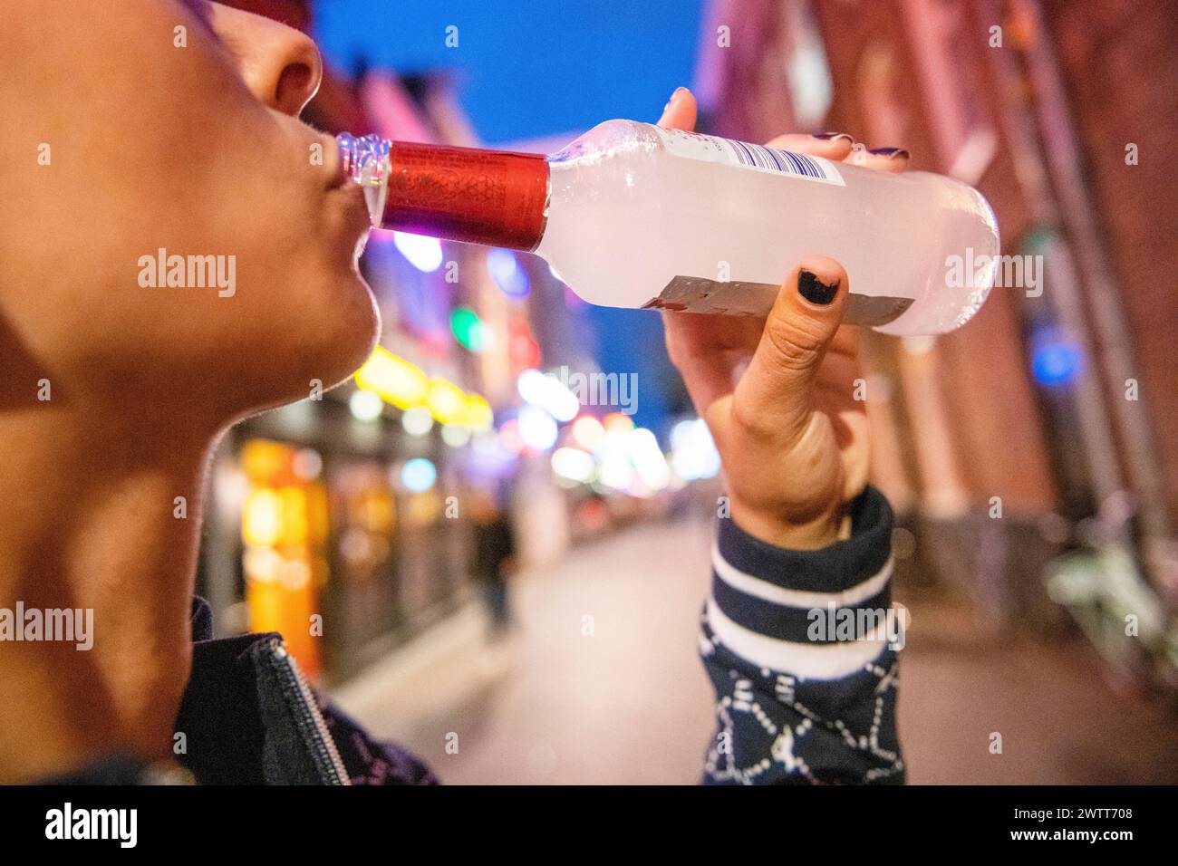 Quenching thirst with a cold drink on a lively city street at dusk. Stock Photo