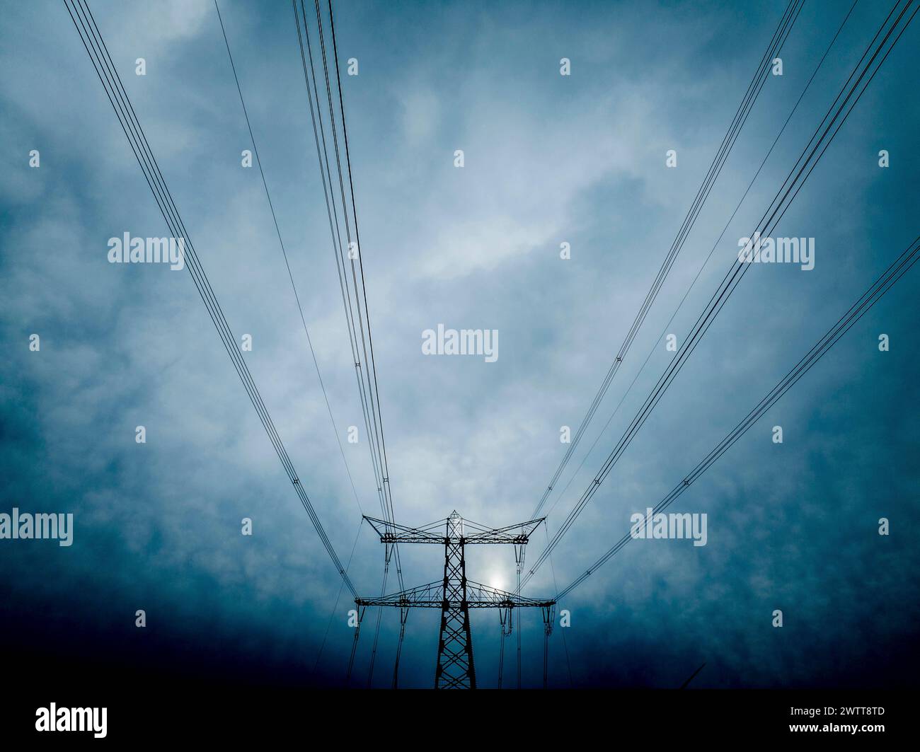 Electricity pylons reaching into a moody sky Stock Photo