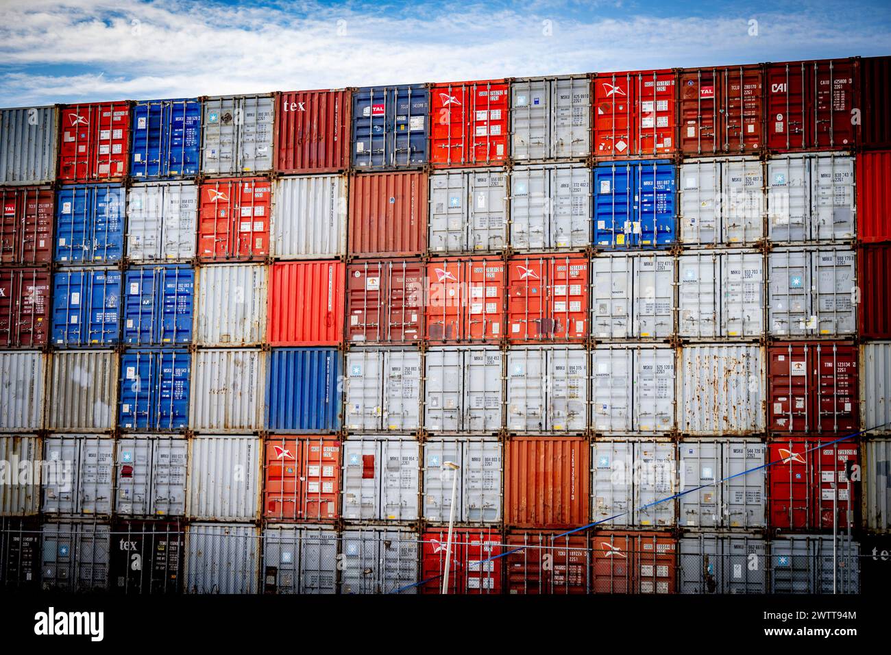 Vibrant maze of stacked shipping containers under a blue sky. Stock Photo