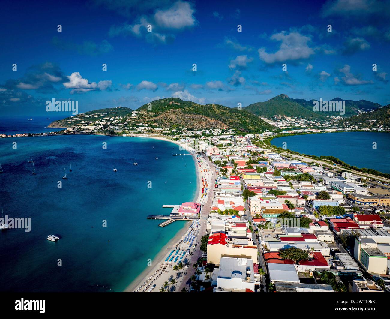 Aerial view of a vibrant coastal town with lush green hills and clear blue waters. Stock Photo