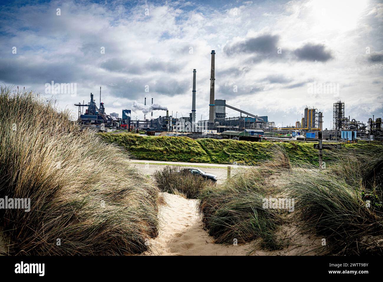 Contrasting elements with a serene beach in the foreground and an industrial landscape in the background Stock Photo
