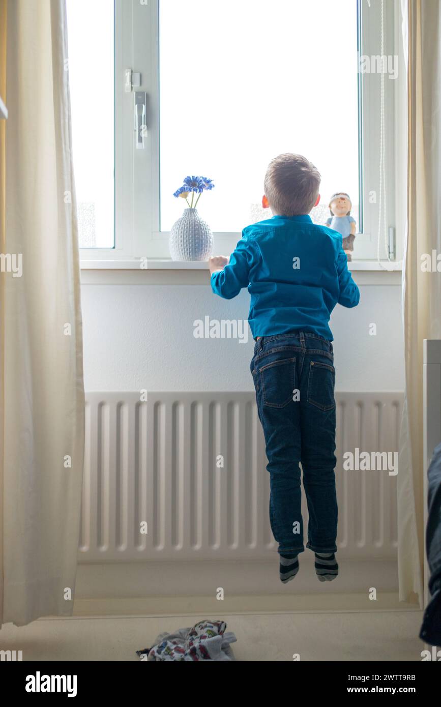 Little boy gazing out the window in anticipation. Stock Photo