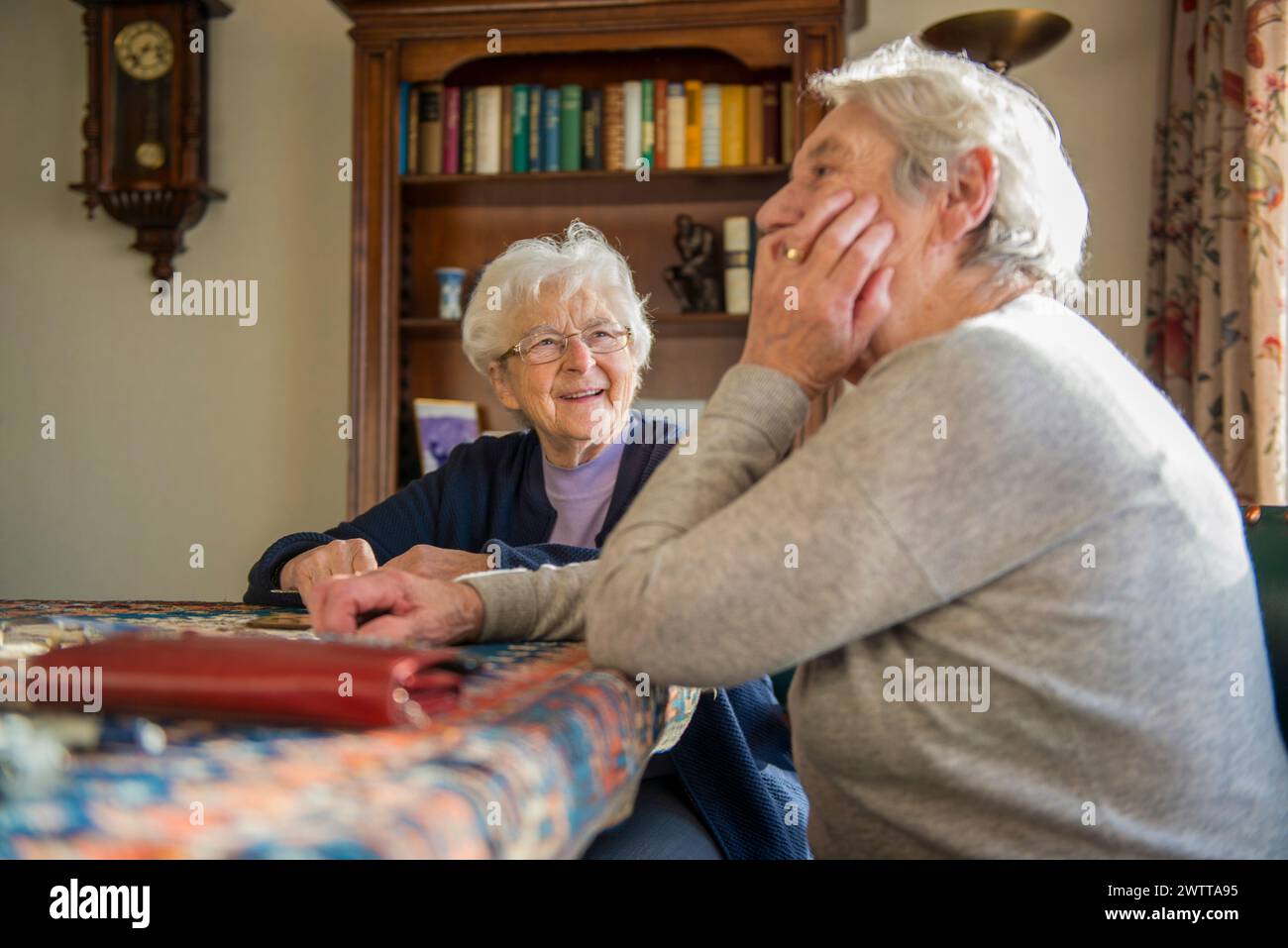 Two elderly women sharing a joyful moment together at home Stock Photo