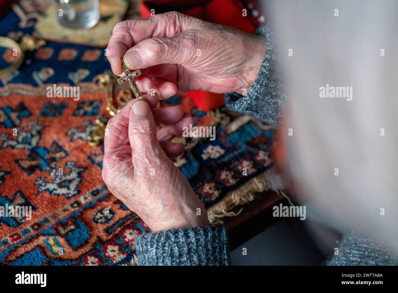 Elderly hands delicately holding a small object with a warm and cozy background Stock Photo