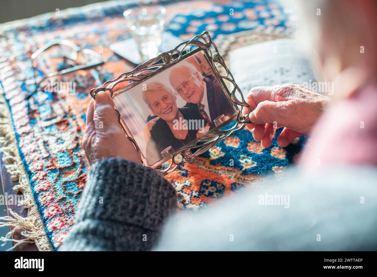 Elderly hands holding a treasured photo frame with an image of an older couple Stock Photo