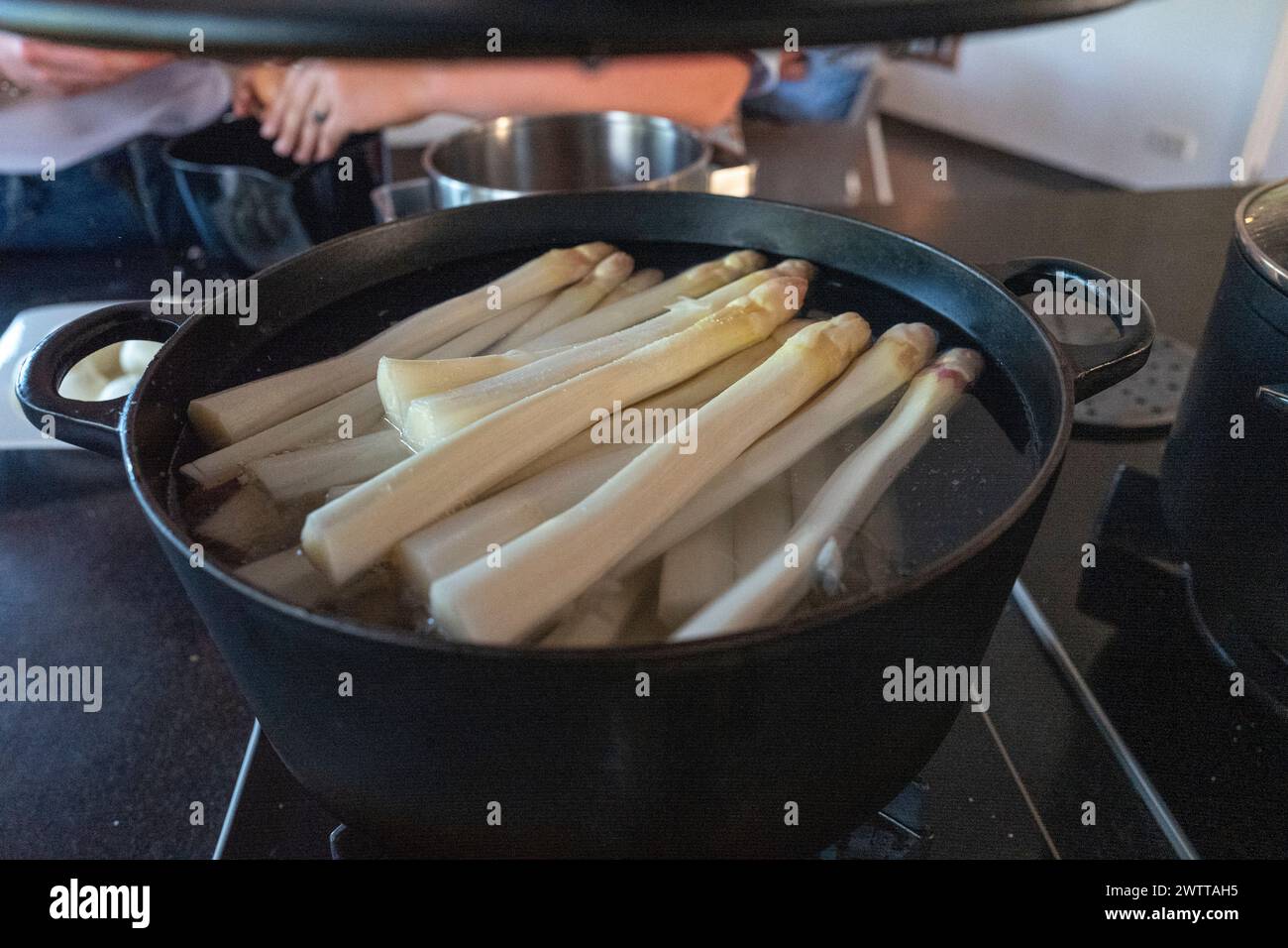 A pot full of fresh asparagus on a stove ready for cooking Stock Photo