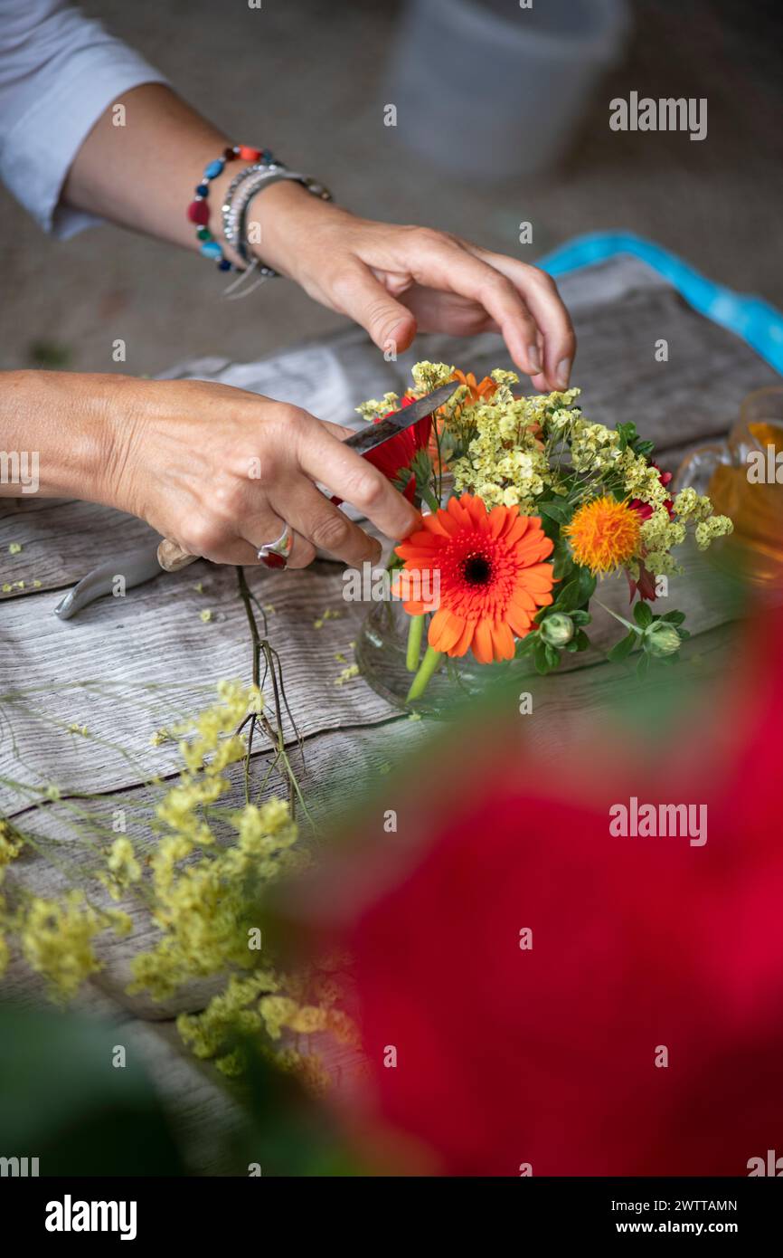 Hands skillfully arranging a colorful floral bouquet on a table. Stock Photo
