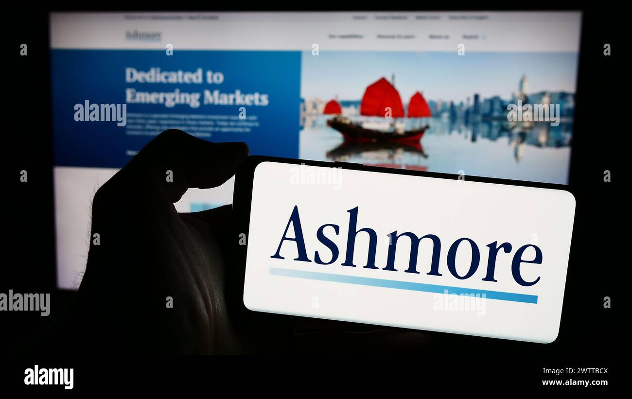 Person holding smartphone with logo of British investment management