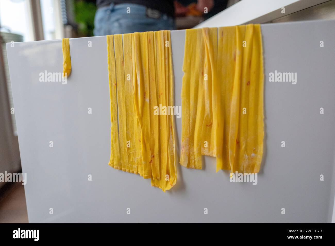 Fresh homemade pasta drying on the edge of a kitchen counter. Stock Photo