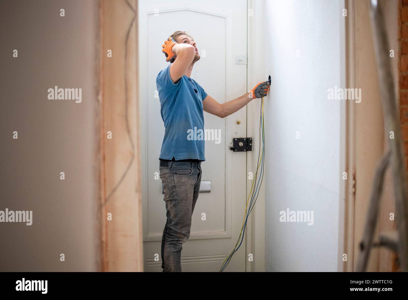 Person drilling into a white door while wearing safety goggles. Stock Photo