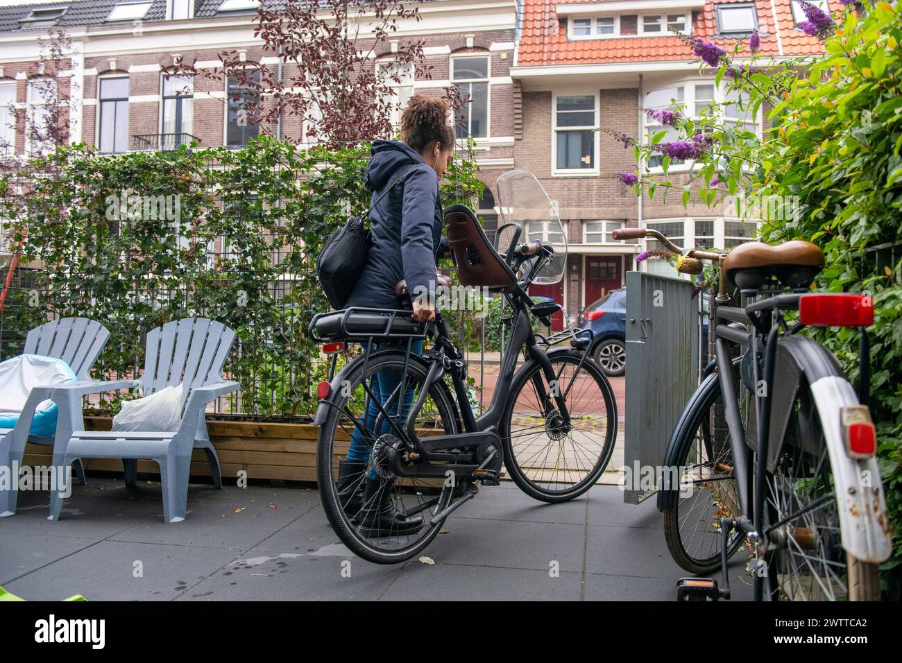 A cyclist pauses by a city bike parked in a quaint European street. Stock Photo