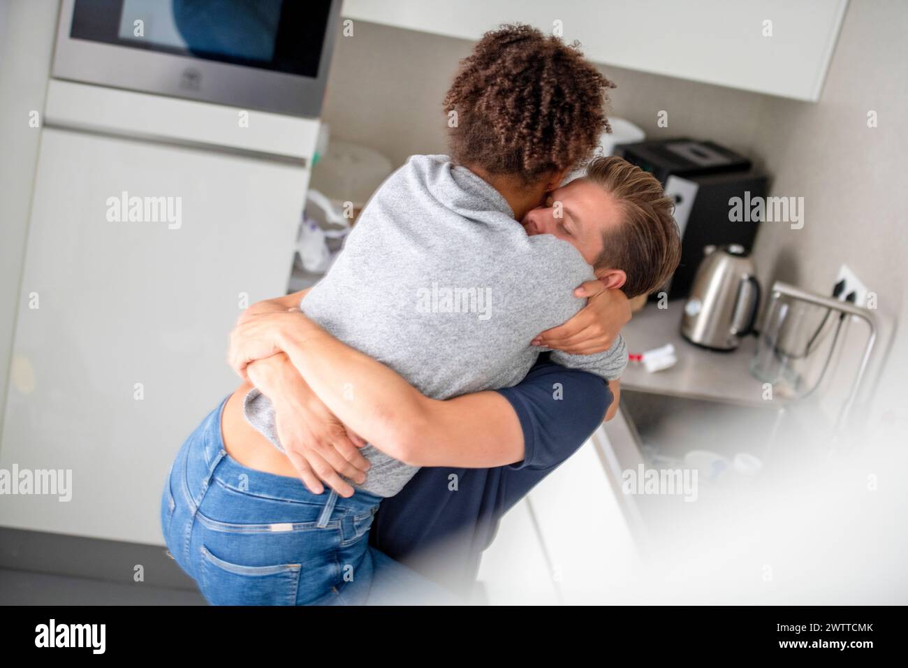 Warm embrace in a bright kitchen setting Stock Photo