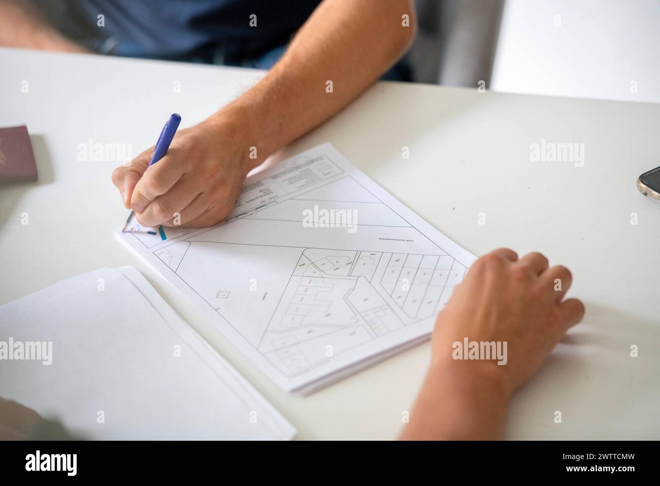 Person sketching architectural plans on a white table. Stock Photo