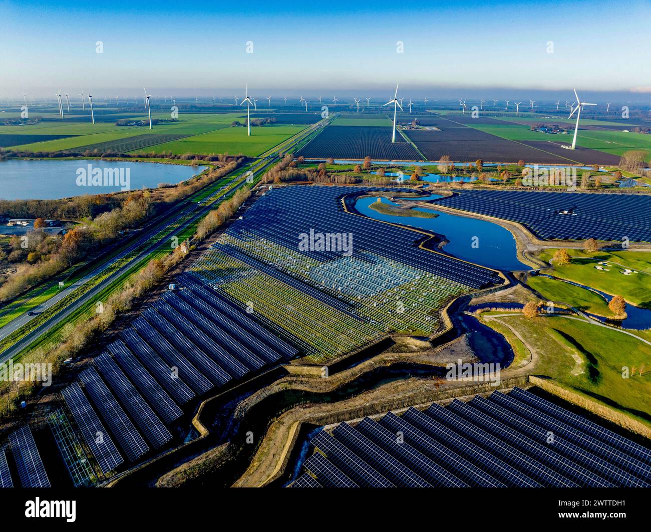 Aerial view of a sprawling solar farm alongside wind turbines in a ...