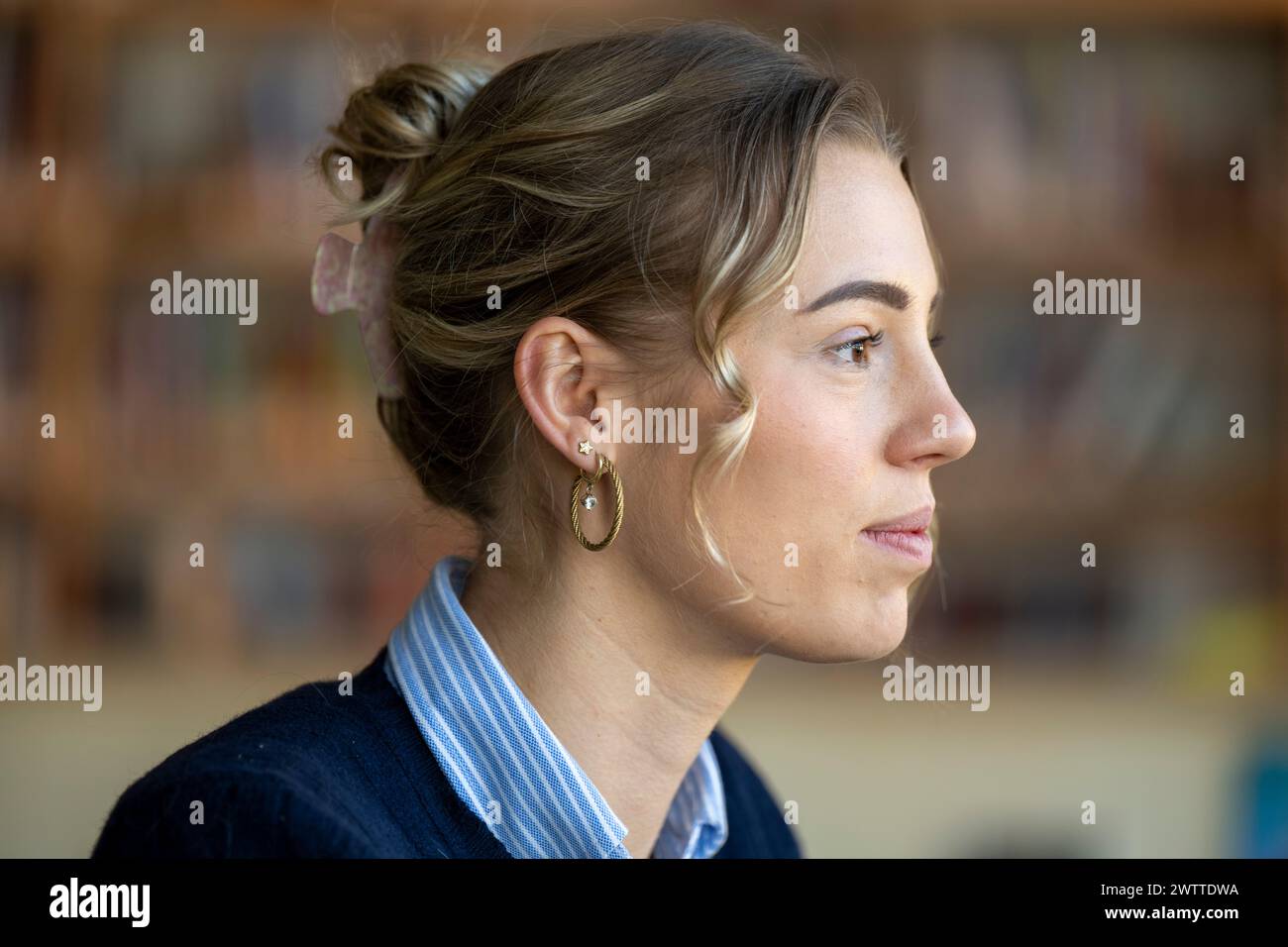 A contemplative young woman in a library setting. Stock Photo