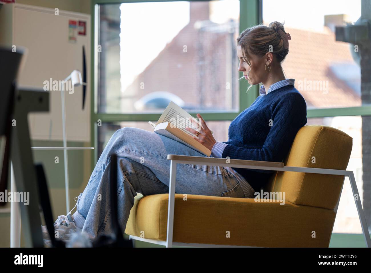 Engrossed in literature by the window Stock Photo
