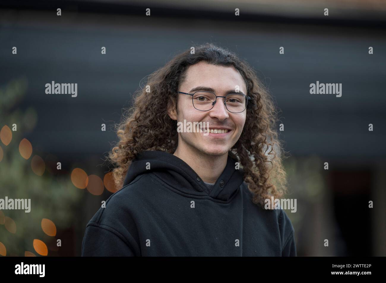 Smiling young person with curly hair enjoying an outdoor moment Stock Photo