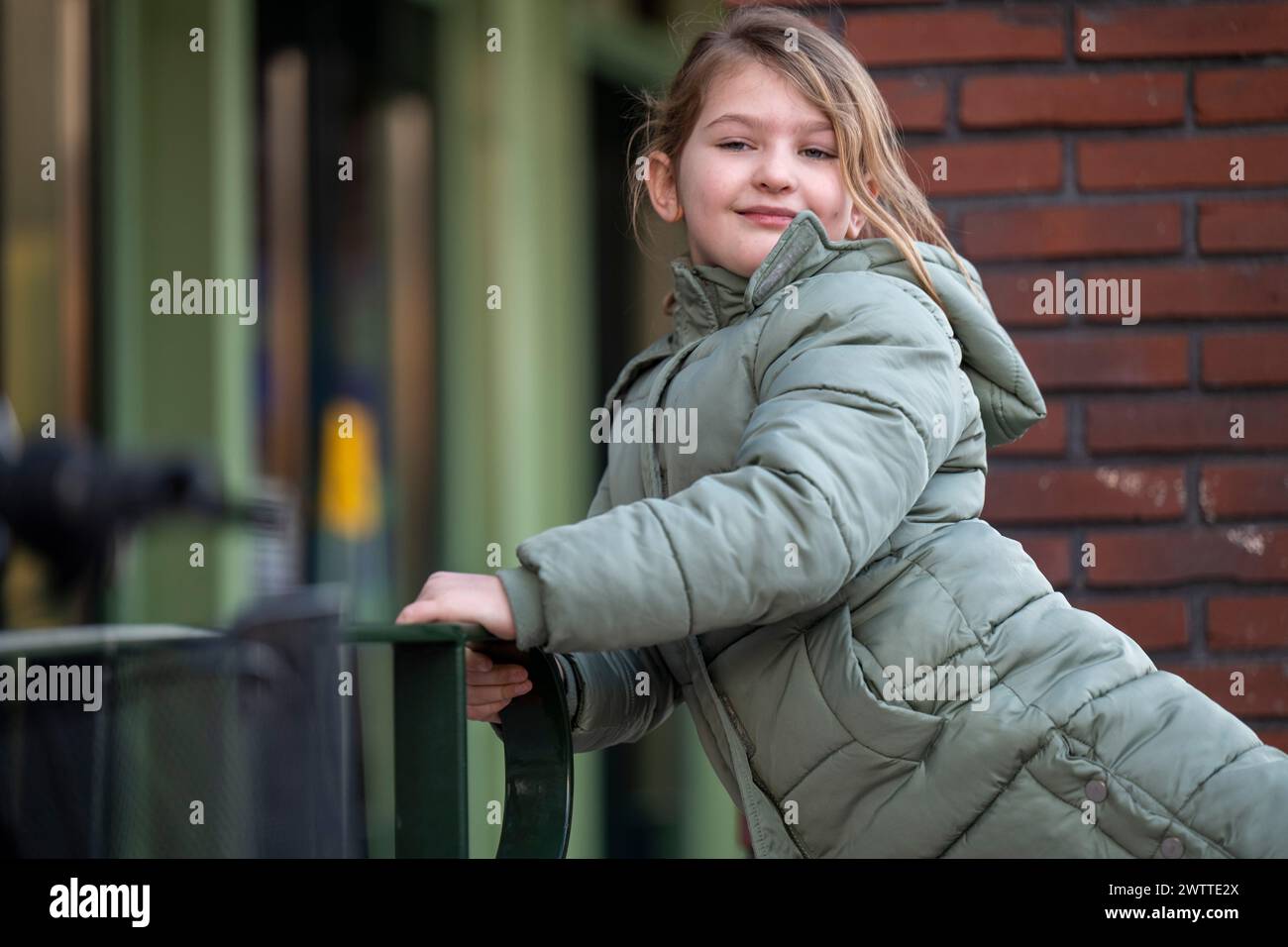 Young girl leaning on a fence with a candid smile Stock Photo