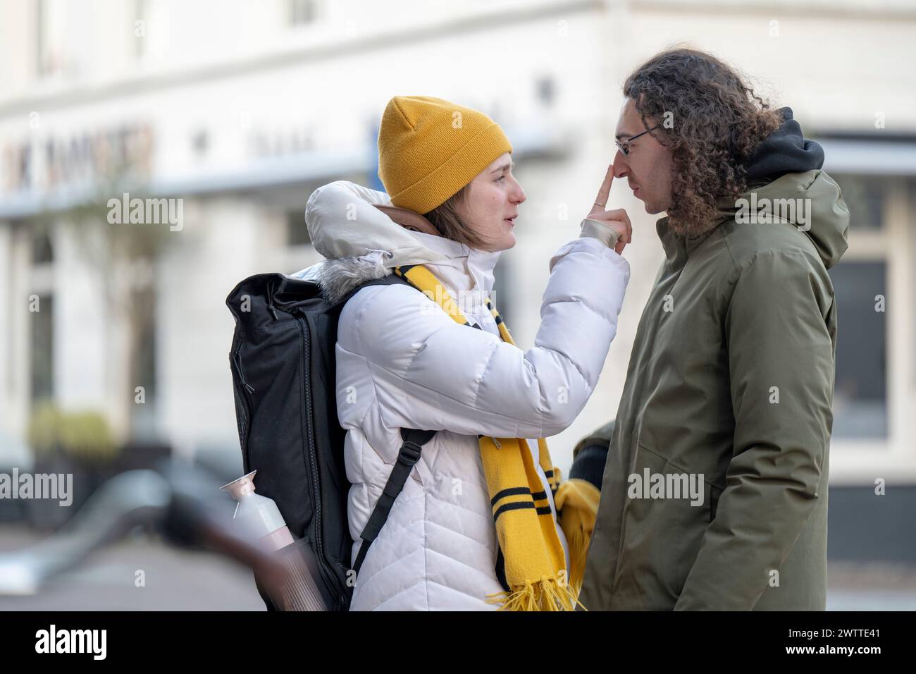 A candid moment of a person playfully touching another person's nose on an urban street. Stock Photo