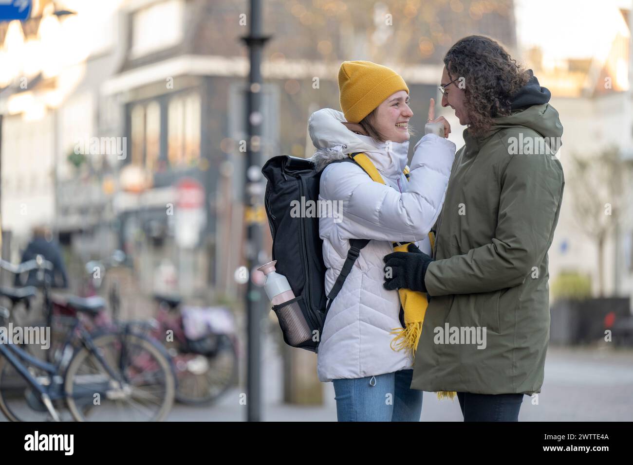 Two friends share a warm moment on a chilly city street. Stock Photo