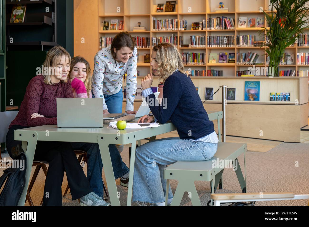 A group of students collaboratively working on a project in a modern library setting. Stock Photo