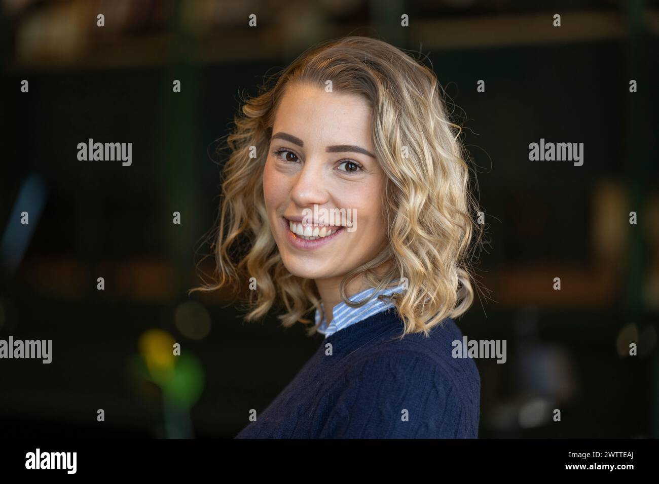 Smiling young woman with curly hair posing indoors Stock Photo
