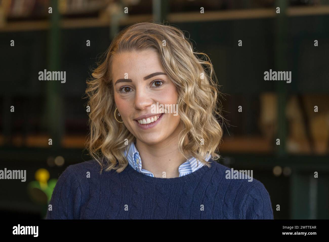 Young woman smiling in a cozy library setting. Stock Photo