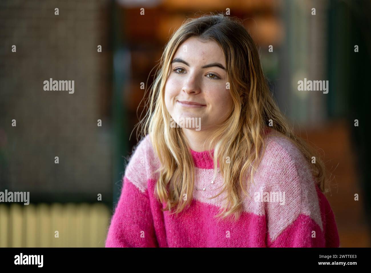 Smiling young woman in a pink sweater enjoying the day outdoors. Stock Photo