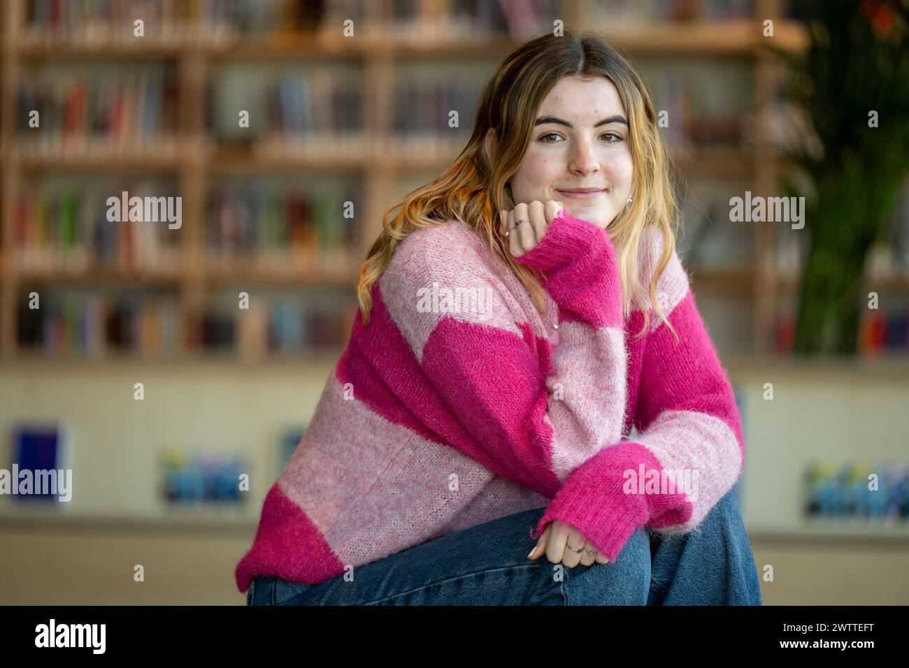 Young woman smiling in a library setting. Stock Photo