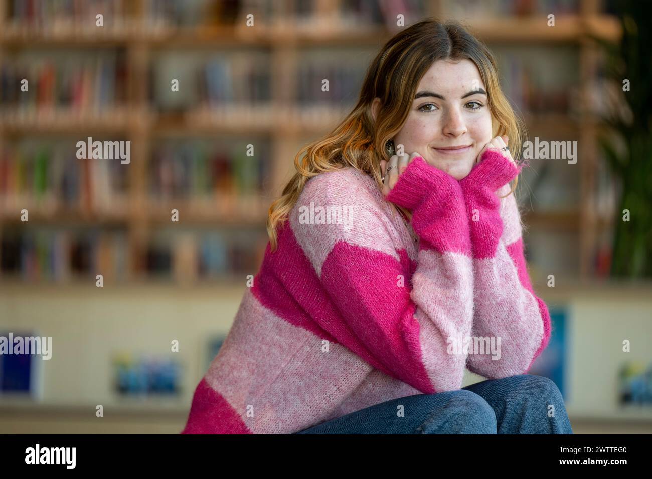 Young woman smiling warmly inside a library Stock Photo