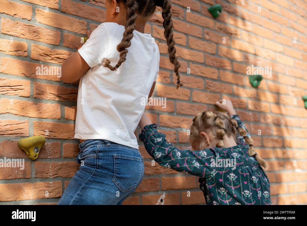 Two children engaged in rock climbing on an artificial climbing wall. Stock Photo