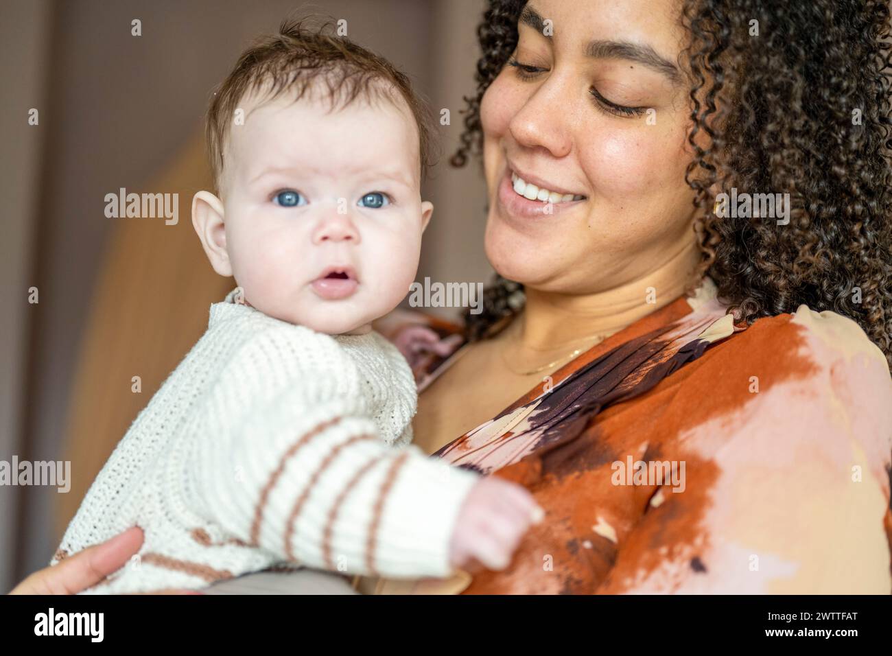 A mother cradles her baby with a tender smile. Stock Photo