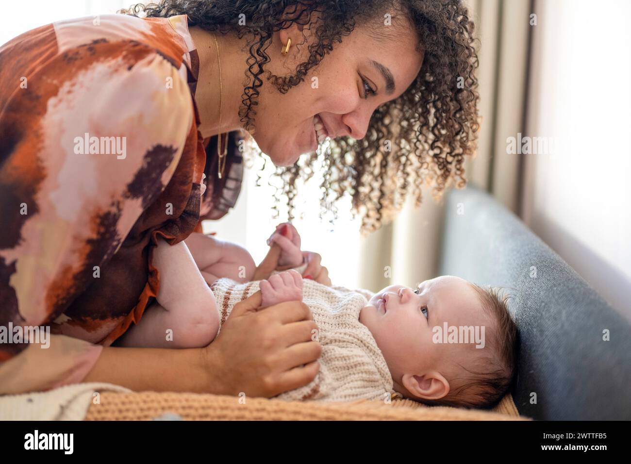 A heartwarming moment as a mother smiles lovingly at her baby. Stock Photo