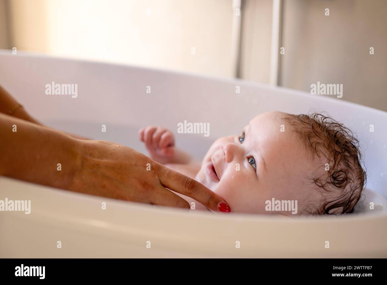 A baby enjoying bath time, gazing up with a look of contentment. Stock Photo