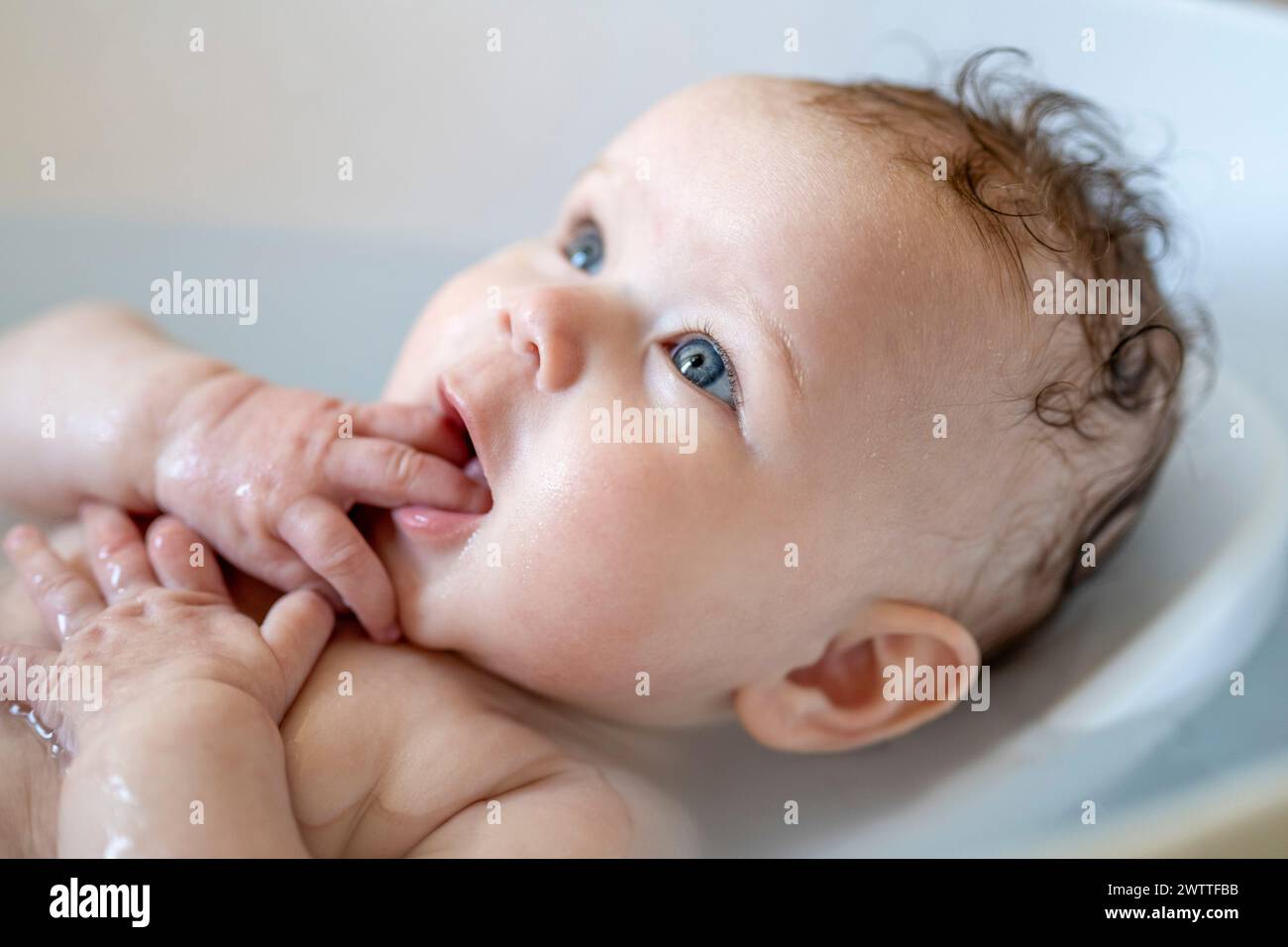Baby enjoying bath time with a curious gaze. Stock Photo