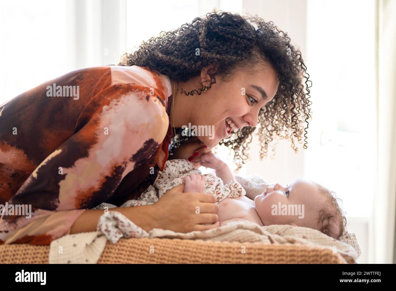 A joyful moment between mother and baby bathed in soft light. Stock Photo
