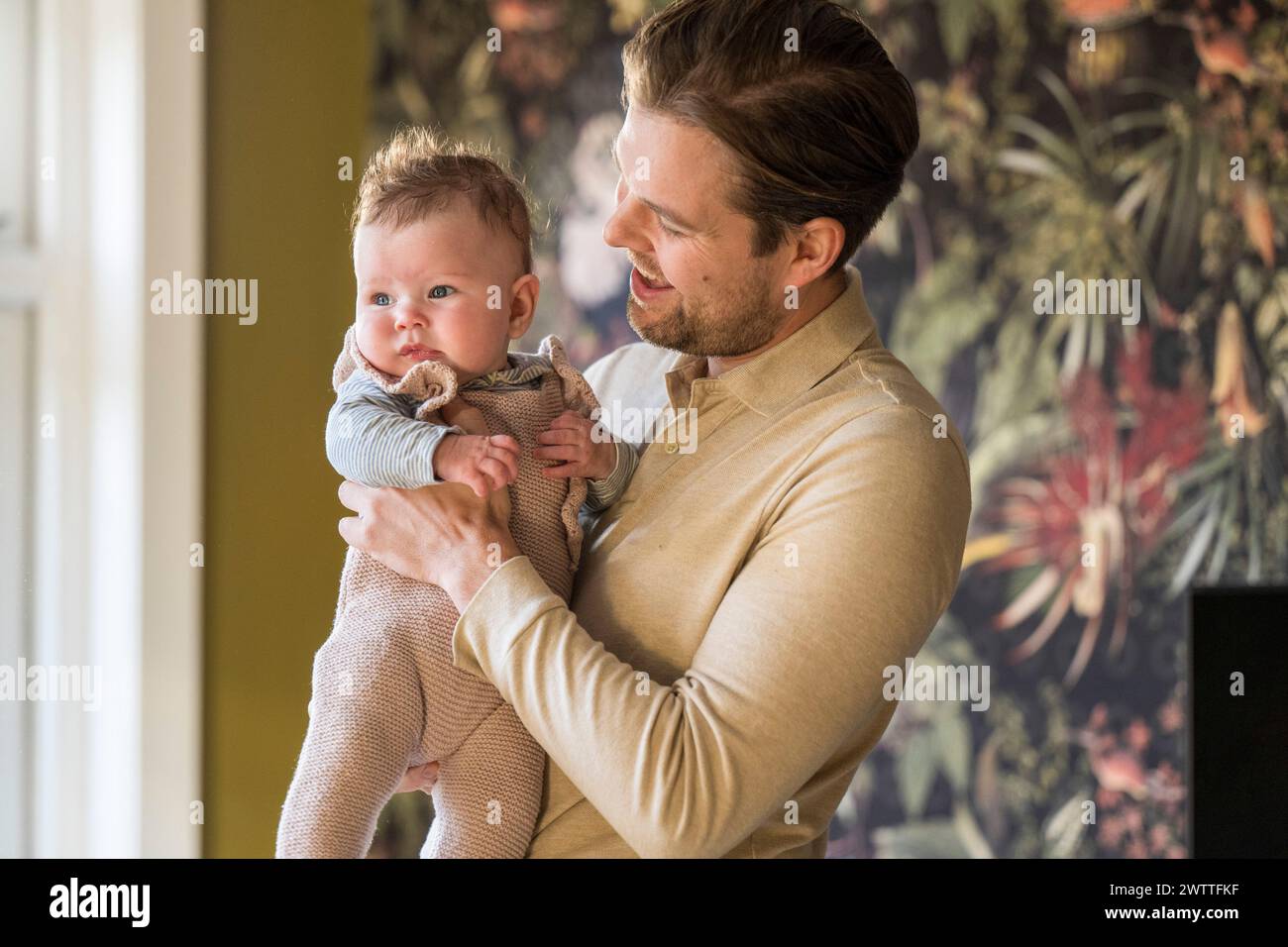 A heartwarming moment as a father holds his baby at home. Stock Photo