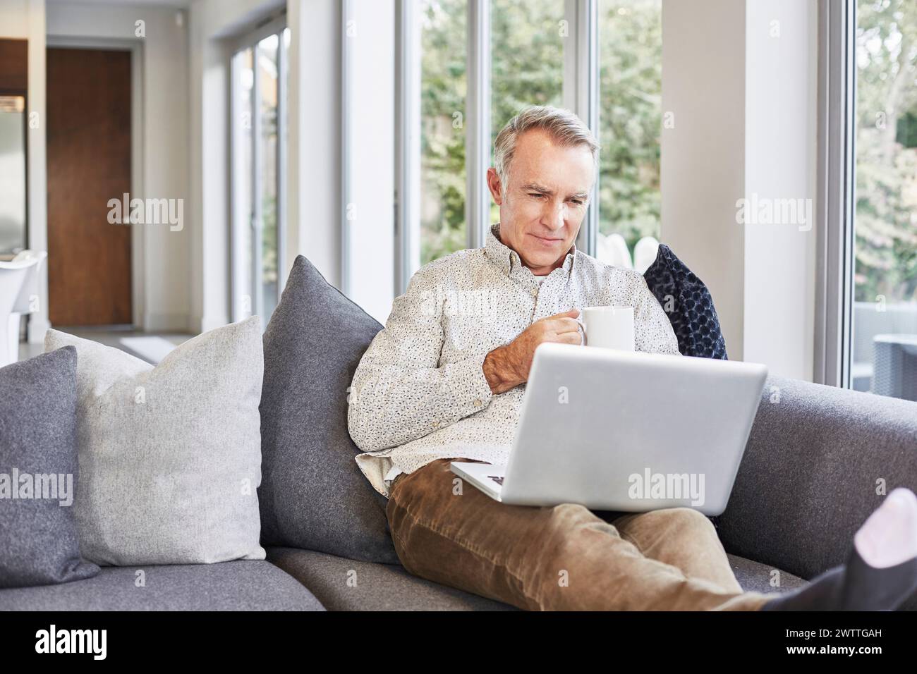 Man working on laptop while sitting on a couch Stock Photo
