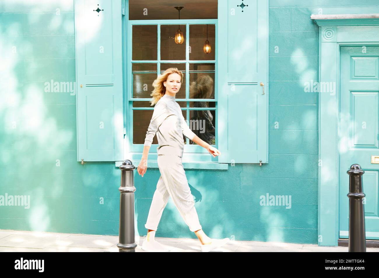 Woman walking by a teal door Stock Photo