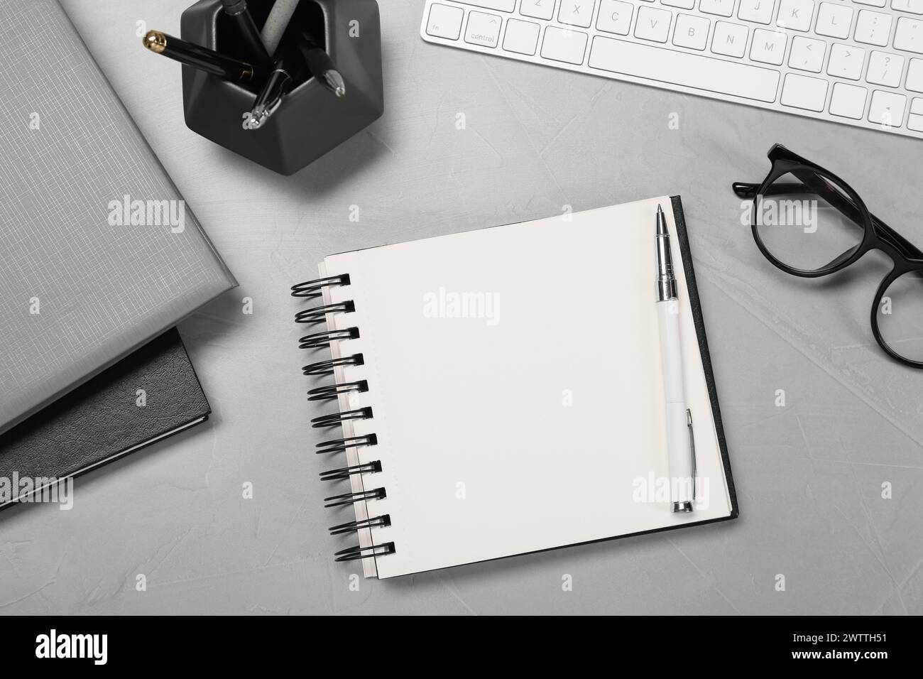 Flat lay composition with notebooks, keyboard and glasses on light grey table Stock Photo