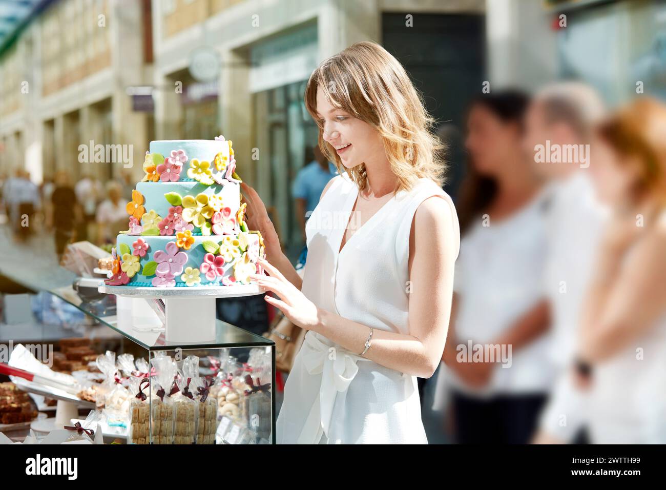 Woman admiring a colorful cake at a bakery Stock Photo