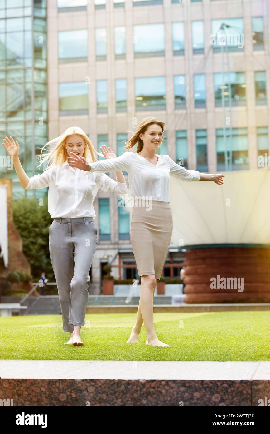 Two women running barefoot on grass Stock Photo
