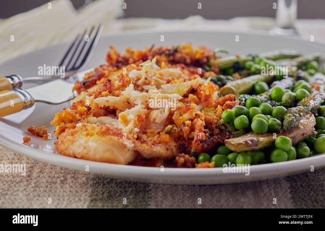 Breaded fish fillet with garden peas and asparagus. Stock Photo